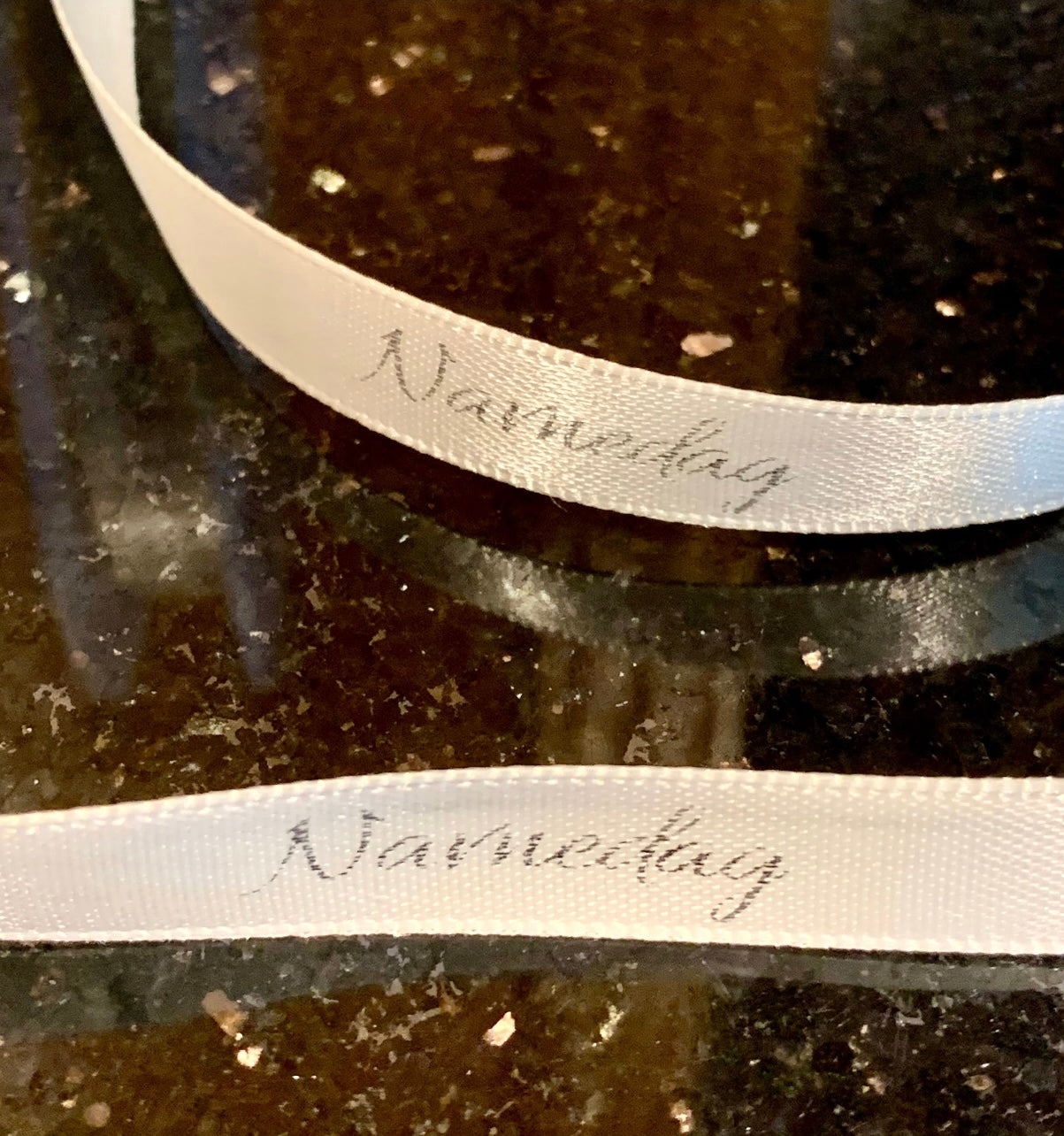 Bånd med tekst «Navnedag», offwhite m/sølvskrift. 10mm