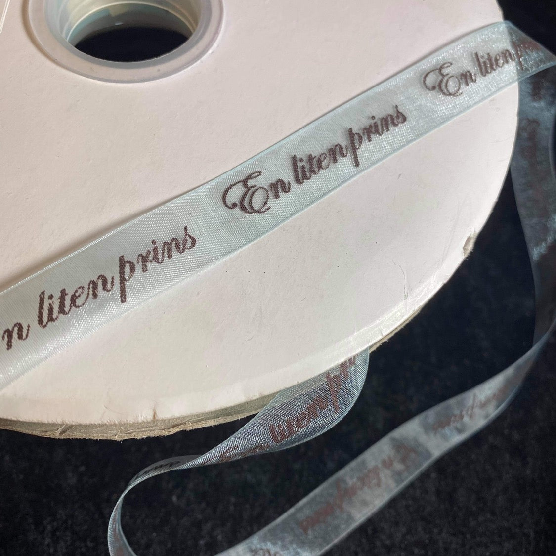 Bånd med tekst «En liten prins», sheerbånd lysblått m/svart tekst . 16mm