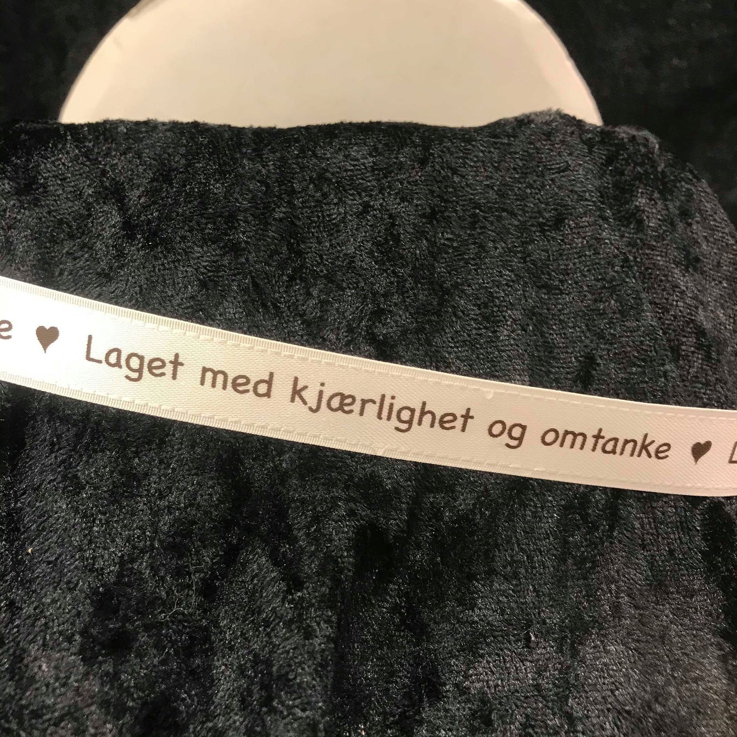 Bånd med tekst. Kremhvitt silkebånd med mørkebrun skrift - "Laget med kjærlighet og omtanke"