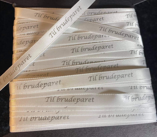 Bånd med tekst «Til brudeparet», hvitt m/sølvskrift. B:10mm.