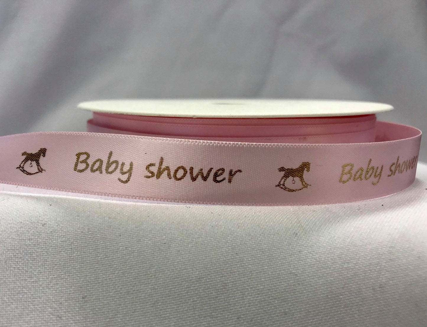Bånd med tekst «Baby shower», lys rosa m/gullskrift. 15mm.