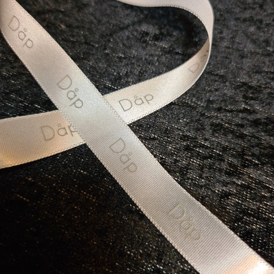 Bånd med tekst «Dåp» hvitt med grå skrift, bredde: 13mm. Pris pr meter.