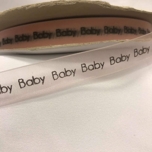 Bånd med tekst « Baby », lys rosa sheerbånd m/svart tekst. 16mm