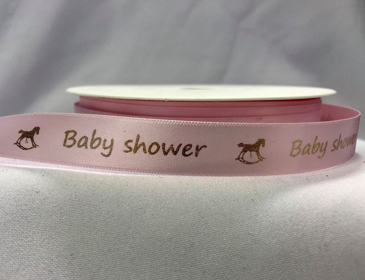 Bånd med tekst «Baby shower», lys rosa m/gullskrift.  15mm.